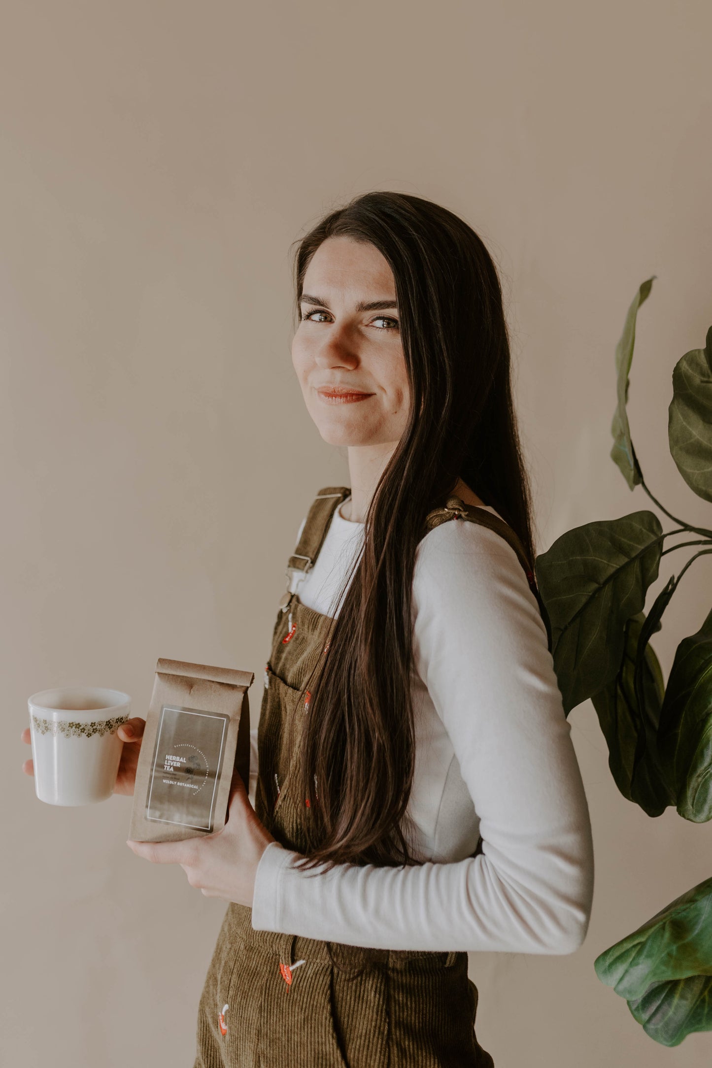 girl with long brown hair, white shirt and mushroom overalls, tea, hot tea, herbal tea, white cup
